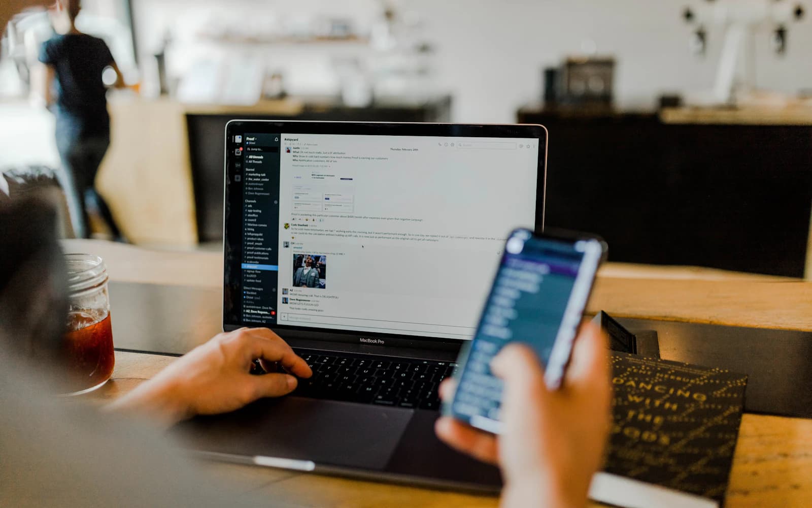 Marketer working across a laptop and phone in a cafe