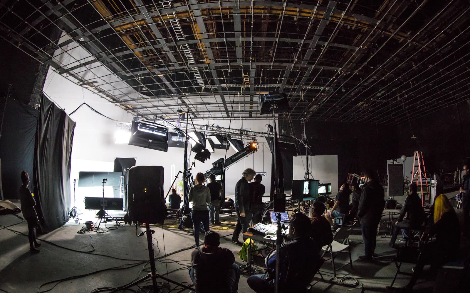 Film crew on a soundstage surrounded by lighting rigs